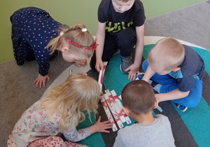 Dzieci układają puzzle patriotyczne w grupie.